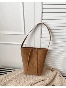 Gros plan détaillé du sac seau en daim marron sur une couverture en laine blanche