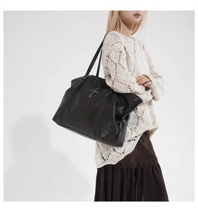 Detail of gothic style tote bag with metal cross and star rivets on textured black leather