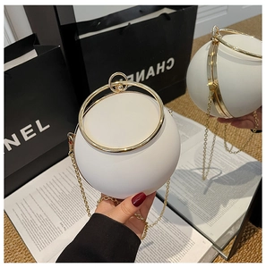 Detail of white spherical evening bag with golden ring handle and elegant metal chain