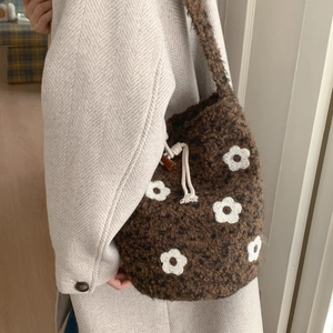 Detail of plush dark brown bucket bag with white floral pattern and drawstring closure