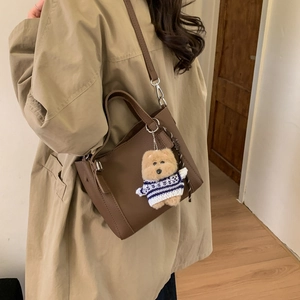 Brown litchi leather bucket bag detail with removable strap and cute teddy bear charm