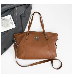 Detail of caramel brown leather tote bag with gothic cross and star metal charms