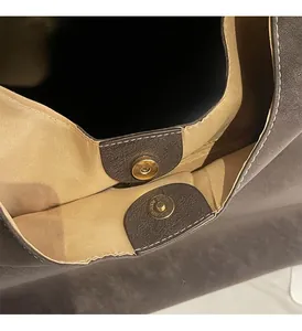 Detail of vintage tote bag showing golden magnetic clasp and textured brown leather material
