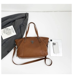 Brown faux leather tote bag showing large capacity with adjustable straps and metal cross