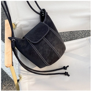 Detail of vintage black bucket bag with white contrast stitching on an outdoor chair