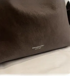 Close-up of pebble grain dark brown leather tote with silver brand logo detailing
