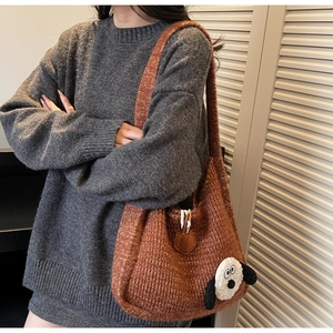 Detail of rust brown knitted hobo bag featuring a 3D plush cartoon dog patch