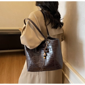 Detail of deep brown crocodile embossed tote bag with fringe and shoulder strap on model