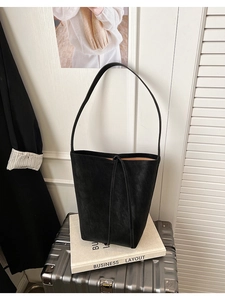 Grand sac fourre-tout en cuir noir avec fermeture à cordon sur une valise argentée