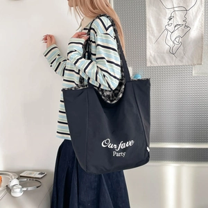 Detail view of large black tote bag featuring white script and cozy faux fur lining