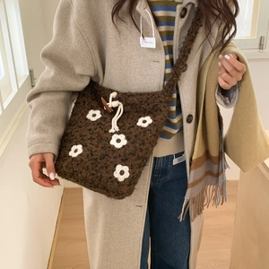 Close-up of brown plush crossbody bag with white crochet flowers and drawstring closure