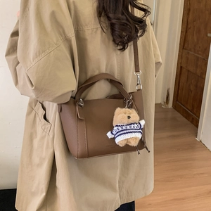 Detail of brown leather bucket bag with cute bear charm and adjustable shoulder strap