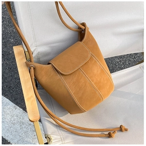 Detail of camel suede bucket bag with contrast white stitching on a folding chair