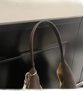 Detail view of the brown suede tote bag featuring slim round handles and silver ring hardware