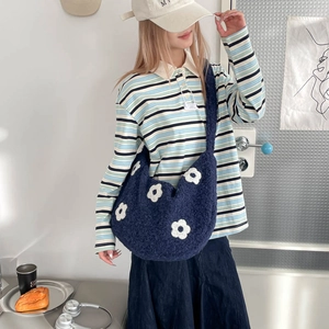 Détail du sac bandoulière en peluche bleu marine avec motifs fleurs blanches sur modèle
