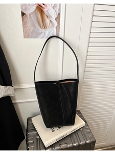 Détail du sac cabas en cuir noir minimaliste avec fermeture à cordon et fines bandoulières