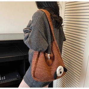 Detail of warm orange knitted tote bag with cute plush dog patch on a shoulder strap