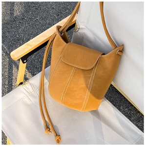 Detail shot of a tan leather bucket bag with white contrast stitching on a folding chair