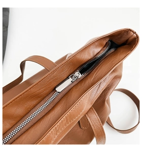 Macro detail of brown litchi pattern leather bag showing silver metal zipper quality
