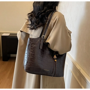 Detail of dark brown faux crocodile leather texture and beaded tassel on the tote bag