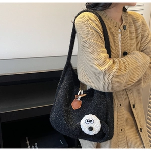 Detail of black knit tote bag with 3D animal design and leather toggle button closure