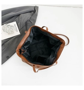 Top view of large brown faux leather tote bag showing spacious black fabric interior and pocket
