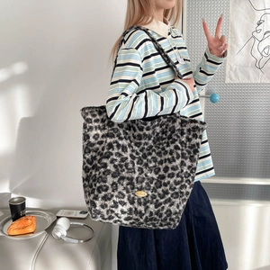 Detail of grey leopard print tote bag with handmade gold metal tag and soft plush texture