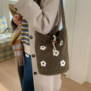Detail of dark brown knitted tote bag with white flower embroidery and wooden toggle closure