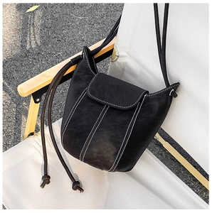 Detail of vintage black leather bucket bag with white contrast stitching on folding chair