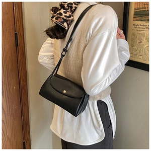 Detail view of black lychee grain square bag with gold magnetic buckle and shoulder strap