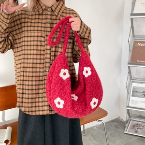 Détail du sac cabas en tricot rouge avec fleurs blanches et texture en peluche douce