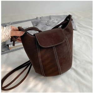 Detail view of a vintage dark brown leather bucket bag with white contrast stitching