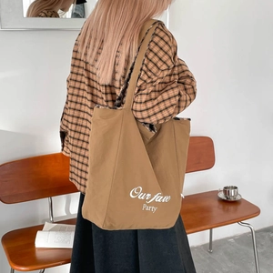 Detail of a brown tote bag with leopard print lining and white typography on a bench