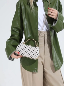 Vintage polka dot box bag with gold frame and chain strap carried by fashion model