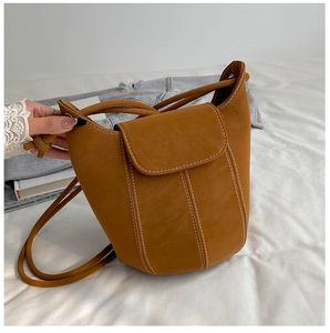 Detail of caramel leather bucket bag featuring white contrast stitching and flap closure
