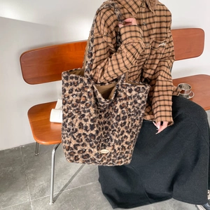 Detail of plush leopard print tote bag featuring a handmade gold metal brand plate