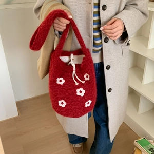 Detail of red plush handbag showing soft knitted texture and white flower patterns