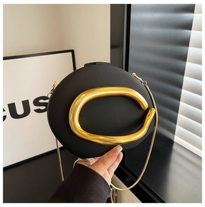 Detail of matte black acrylic clutch with bold gold sculptural clasp and chain strap
