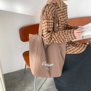 Brown canvas tote bag with white Outave Pay lettering in a retro academic style scene