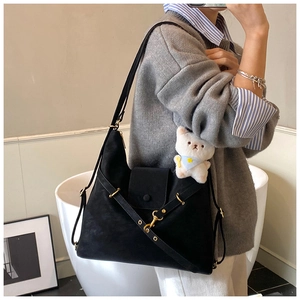 Detail of a large black matte tote bag with magnetic flap and white bear charm
