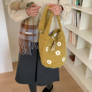 Detail of yellow plush handbag with floral accents and a check wool scarf accessory