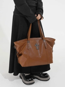 Large brown leather tote bag with metal cross pendant and rivet details for daily commute