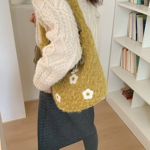 Close-up of yellow fluffy faux fur tote bag featuring white floral knit patterns