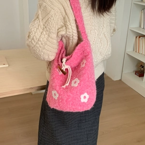 Close-up of pink fluffy knit bucket bag with white floral pattern and drawstring