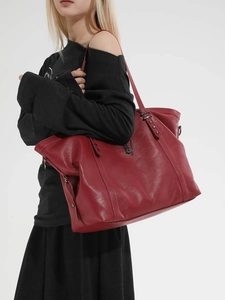 Red large capacity faux leather tote bag with star rivets shown on a female model