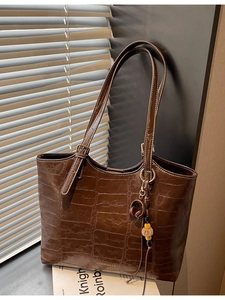 Dark brown faux crocodile tote bag with adjustable strap and chic charm on side
