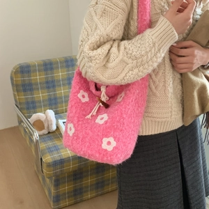 Detailed view of pink plush crossbody bag with flower patterns and horn toggle closure