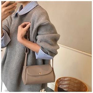 Close-up of beige litchi grain leather crossbody bag with elegant gold round buckle