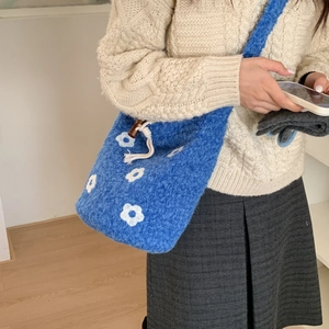 Detail of blue plush crossbody bag with white flower pattern and wooden drawstring bead