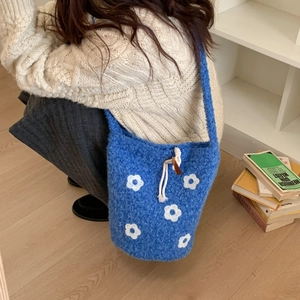 Detailed close-up of blue plush knit bucket bag with white floral pattern and drawstring